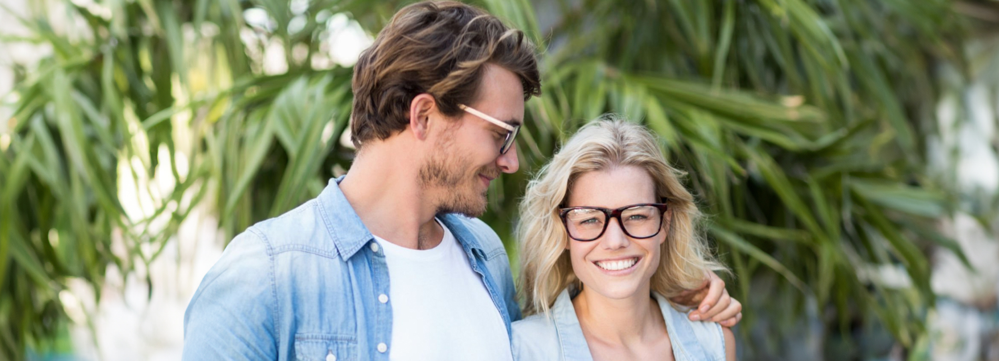 A smiling couple wearing glasses outdoors